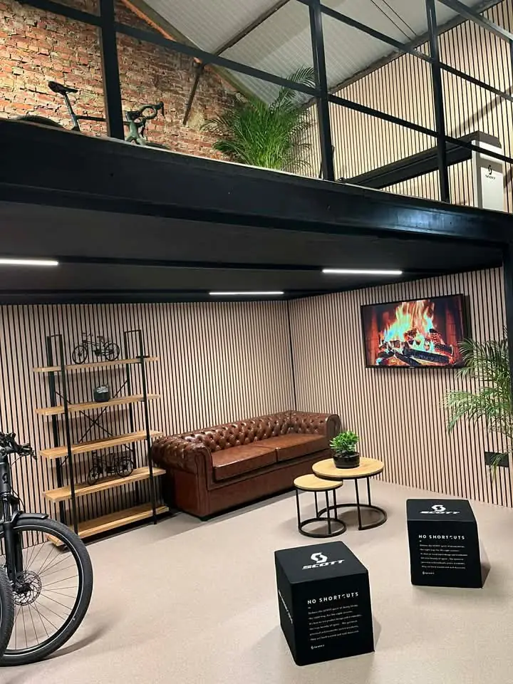 Gezellige zithoek met een bruine lederen bank, planten en houten wandbekleding